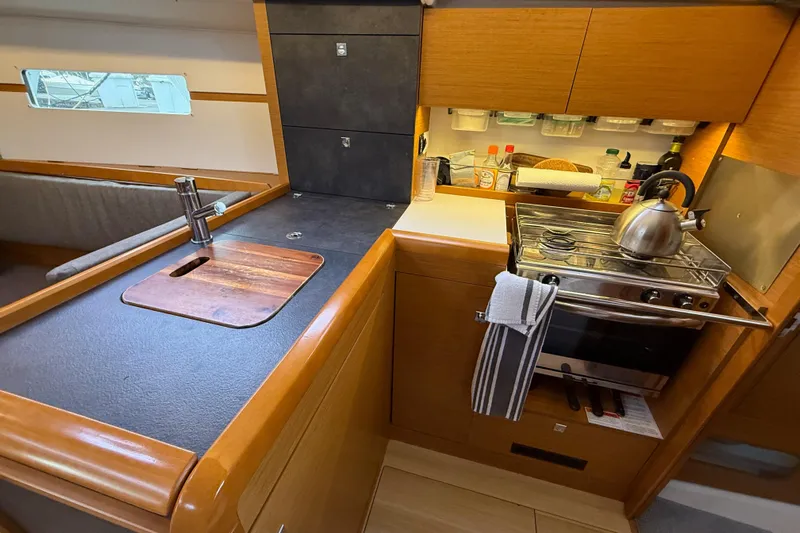 A Bientot Yacht Photos Pics Compact kitchen in 2016 Jeanneau Sun Odyssey 349 sailboat with stove, sink, and storage.