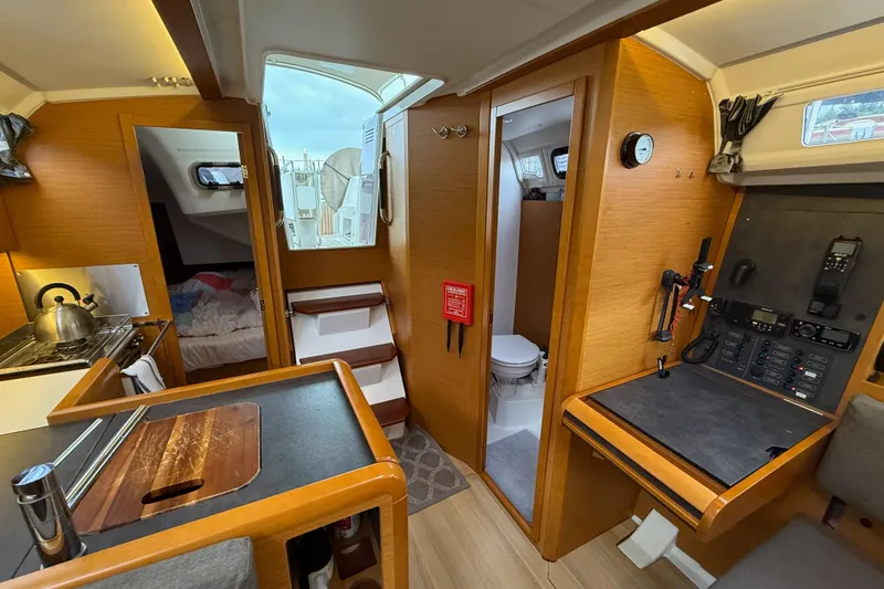 A Bientot Yacht Photos Pics Interior of 2016 Jeanneau Sun Odyssey 349 sailboat, featuring kitchen, navigation station, and cozy cabin.