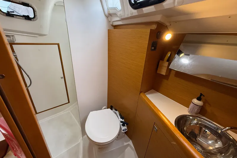 A Bientot Yacht Photos Pics 2016 Jeanneau Sun Odyssey 349 bathroom with shower, toilet, sink, and wooden cabinetry.