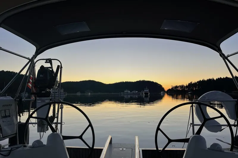 A Bientot Yacht Photos Pics 2016 Jeanneau Sun Odyssey 349 sailboat at sunset, serene water and distant boats.