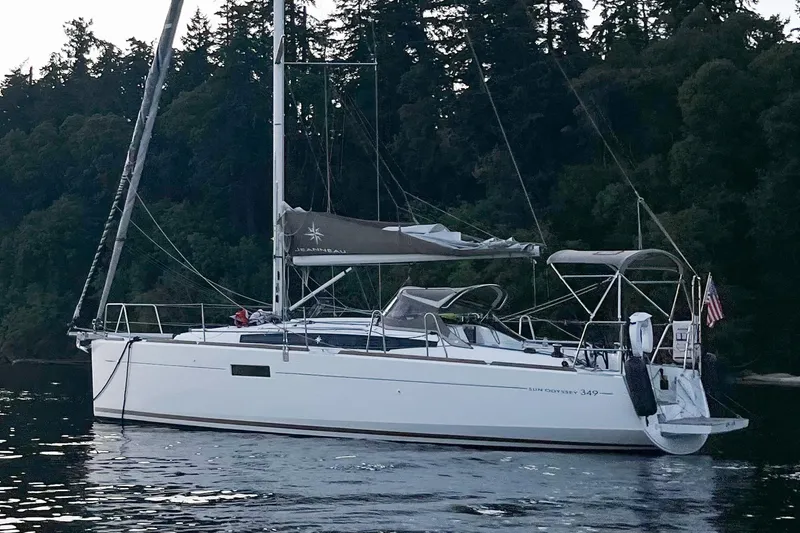 A Bientot Yacht Photos Pics 2016 Jeanneau Sun Odyssey 349 sailboat anchored near forested shoreline.