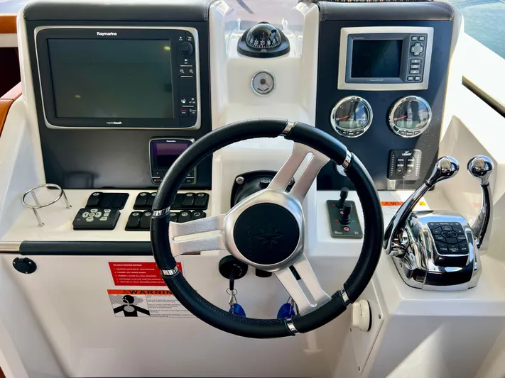 Yacht Photos Pics Control panel of a 2017 Jeanneau Velasco 43 boat with steering wheel and navigation instruments.