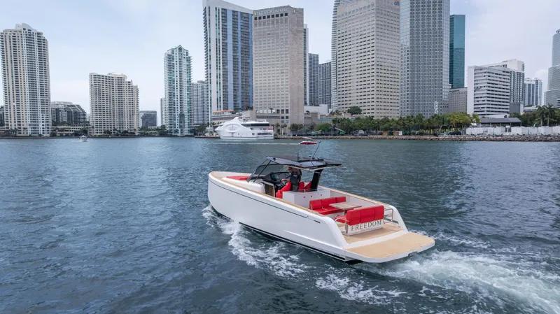 Freedom Yacht Photos Pics 2023 Pardo Yachts 38 cruising near city skyline, featuring sleek design and red seating.