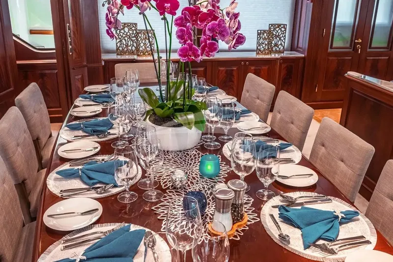 Mamma Mia Yacht Photos Pics Luxurious dining setup on a 2007 Benetti 120 Classic yacht, featuring elegant tableware and orchids.