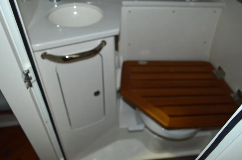  Yacht Photos Pics 2024 Boston Whaler 350 Realm boat bathroom with wooden seat and sink.