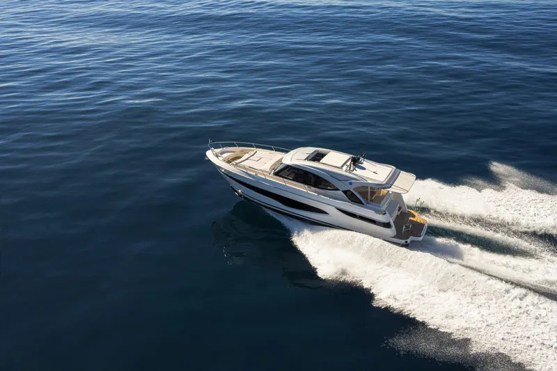  Yacht Photos Pics 2025 Riviera 4300 yacht cruising on open water, creating a dynamic wake.