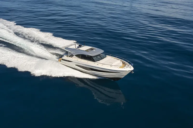  Yacht Photos Pics 2025 Riviera 4300 yacht cruising on open blue water, creating a dynamic wake.