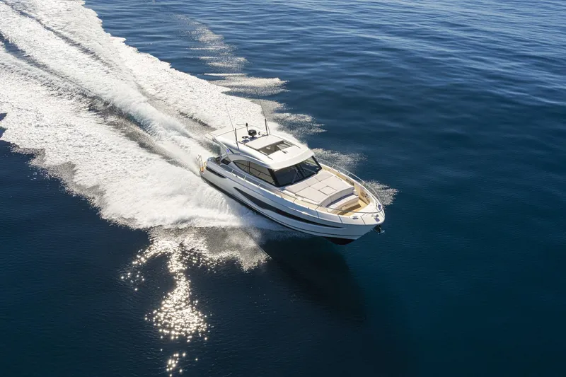  Yacht Photos Pics 2025 Riviera 4300 yacht cruising on open water, leaving a trail of white wake.