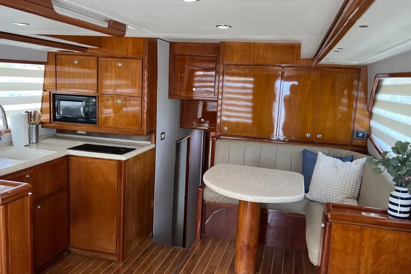 Dream On Yacht Photos Pics Luxurious 2005 Bertram 450 yacht interior with wood cabinetry, kitchenette, and cozy dining area.