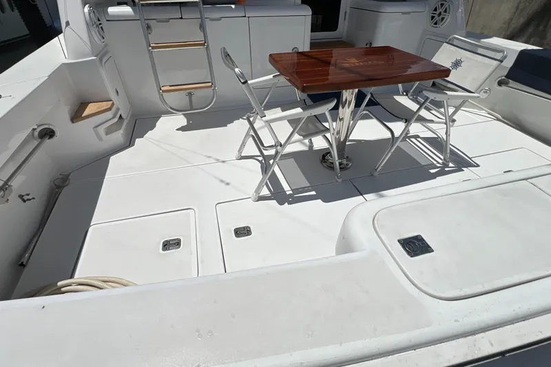 Dream On Yacht Photos Pics 2005 Bertram 450 yacht deck with table and chairs, featuring sleek white design.