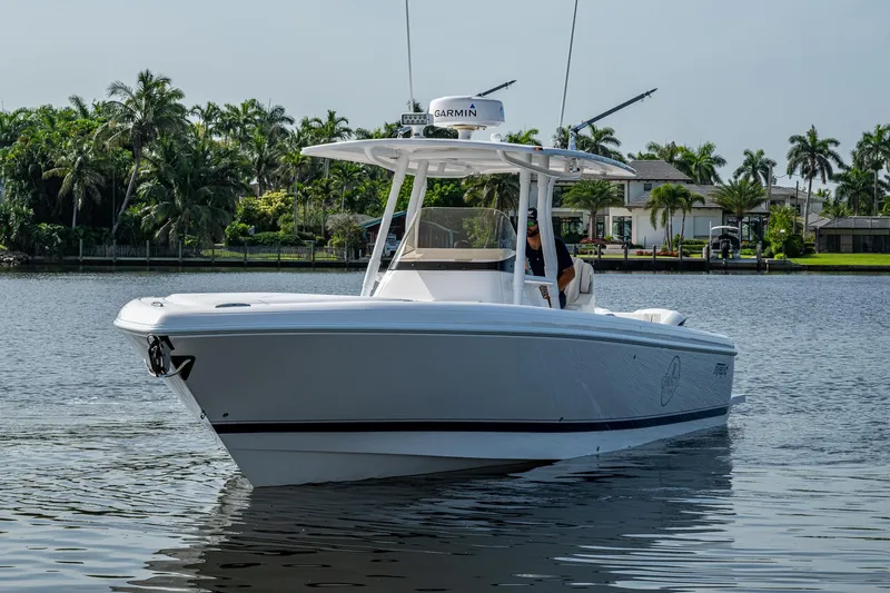 Christyl Clear Yacht Photos Pics 2018 Intrepid 327 Center Console boat on calm water, surrounded by lush greenery.
