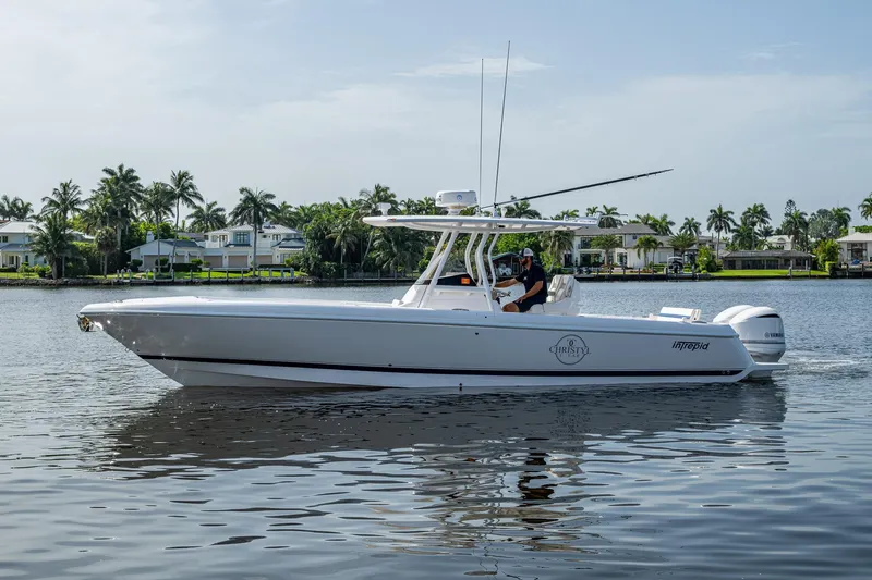 Christyl Clear Yacht Photos Pics 2018 Intrepid 327 Center Console boat cruising on a calm waterway with palm trees in the background.