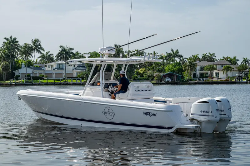 Christyl Clear Yacht Photos Pics 2018 Intrepid 327 Center Console boat on calm water, with palm trees in the background.