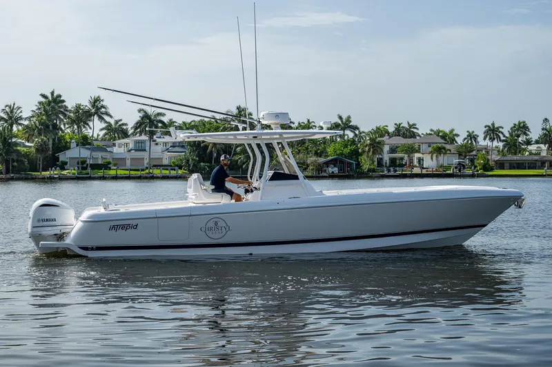 Christyl Clear Yacht Photos Pics 2018 Intrepid 327 Center Console boat on calm water, surrounded by palm trees and houses.