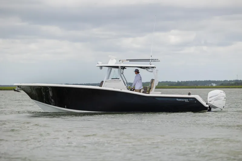  Yacht Photos Pics 2020 Tidewater 320 CC Adventure boat cruising on calm waters under cloudy skies.
