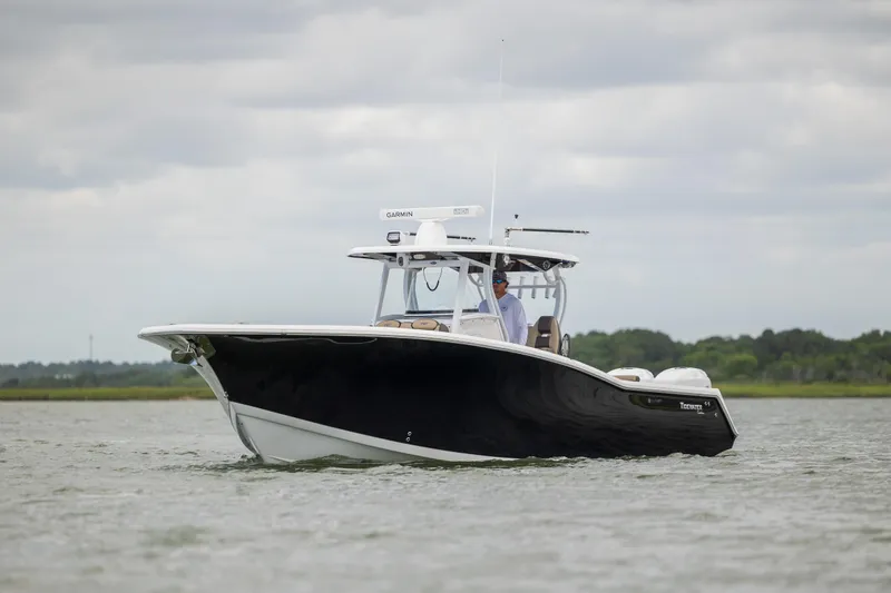  Yacht Photos Pics 2020 Tidewater 320 CC Adventure boat cruising on calm waters under cloudy skies.