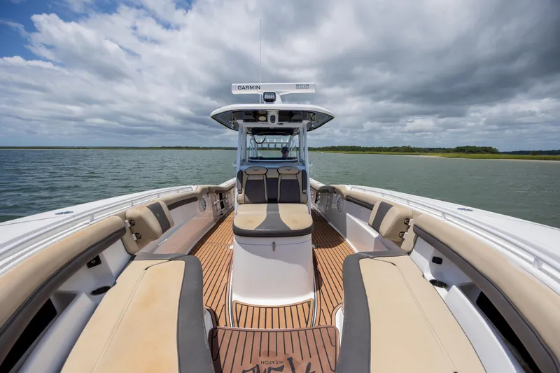  Yacht Photos Pics 2020 Tidewater 320 CC Adventure boat interior with seating, on a calm lake under cloudy skies.