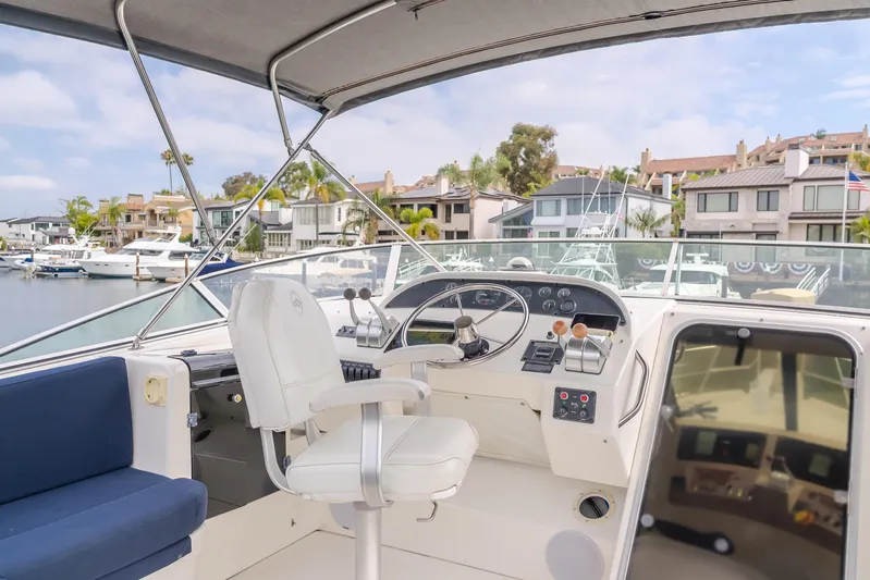 Coffey To Cocktails II Yacht Photos Pics 1998 Bayliner 4788 Pilot House Motoryacht helm with marina view, featuring modern controls and seating.