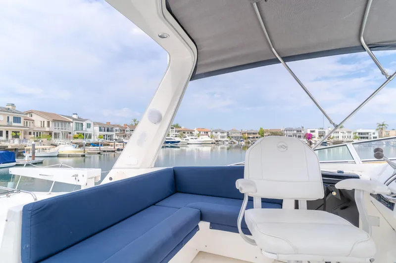 Coffey To Cocktails II Yacht Photos Pics 1998 Bayliner 4788 Pilot House Motoryacht interior with blue seating, overlooking waterfront homes.