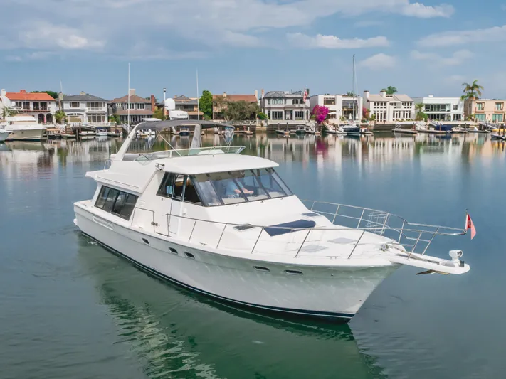 Coffey To Cocktails II Yacht Photos Pics 1998 Bayliner 4788 Pilot House Motoryacht on calm water near waterfront homes.