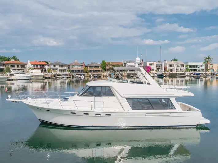 Coffey To Cocktails II Yacht Photos Pics 1998 Bayliner 4788 Pilot House Motoryacht docked in a serene marina setting.