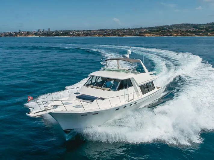 Coffey To Cocktails II Yacht Photos Pics 1998 Bayliner 4788 Pilot House Motoryacht cruising on open water, coastal city in background.