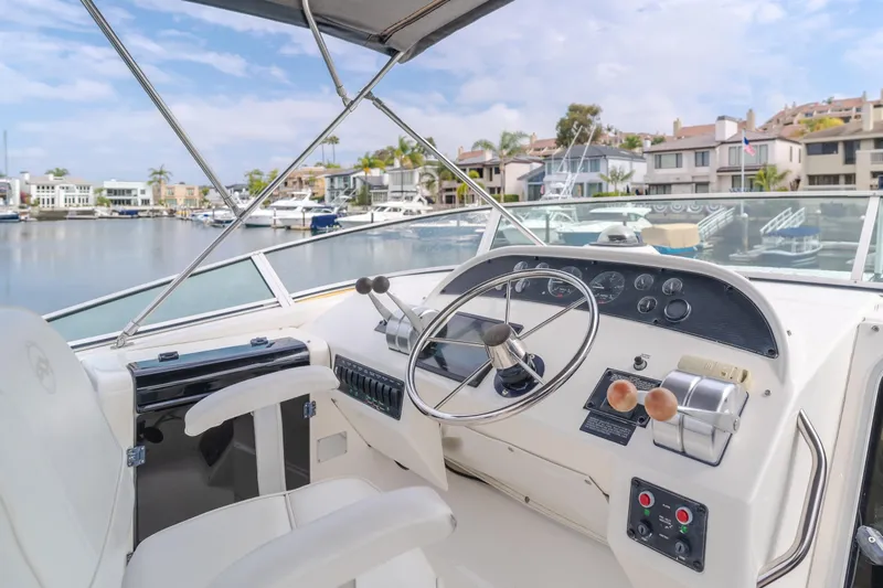 Coffey To Cocktails II Yacht Photos Pics 1998 Bayliner 4788 Pilot House Motoryacht helm with marina view, featuring steering wheel and controls.