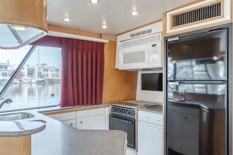 Coffey To Cocktails II Yacht Photos Pics Interior of 1998 Bayliner 4788 Pilot House Motoryacht kitchen with appliances and window view.