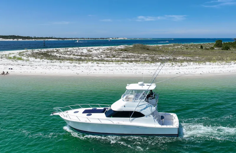 The Callback Yacht Photos Pics 2007 Riviera 42 Flybridge yacht cruising near a sandy beach with clear blue skies.