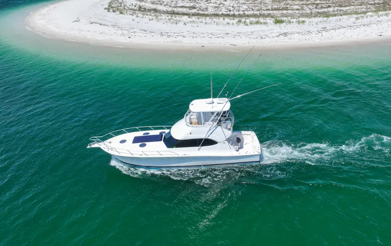 The Callback Yacht Photos Pics 2007 Riviera 42 Flybridge yacht cruising near a sandy beach in clear turquoise waters.