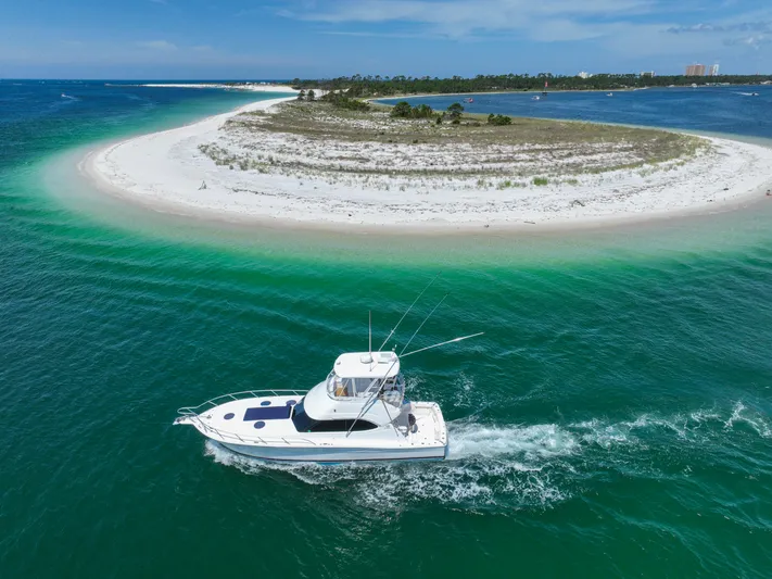 The Callback Yacht Photos Pics 2007 Riviera 42 Flybridge cruising near a sandy island with turquoise waters.