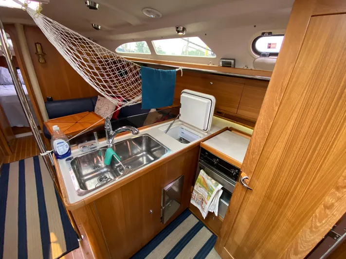  Yacht Photos Pics Interior of 2014 Catalina 355 sailboat kitchen with sink, fridge, and wooden cabinetry.