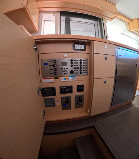 Halia Yacht Photos Pics Control panel inside a 2014 Lagoon 450 catamaran, featuring wooden cabinetry and modern appliances.