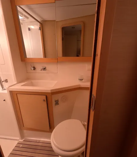 Halia Yacht Photos Pics 2014 Lagoon 450 yacht bathroom with wooden cabinetry, mirror, and compact design.