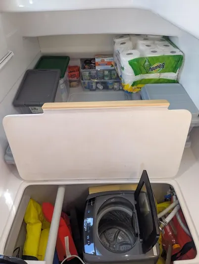 God Speed Yacht Photos Pics Storage area in a 2020 Seawind 1260 yacht with supplies and a compact washing machine.