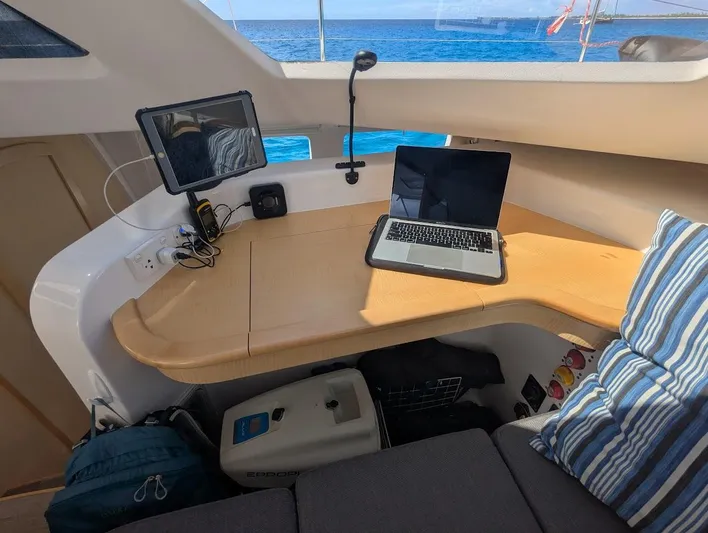 God Speed Yacht Photos Pics Seawind 1260 catamaran interior with laptop and tablet on wooden desk, ocean view.