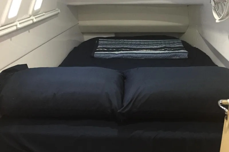 God Speed Yacht Photos Pics 2020 Seawind 1260 cabin interior with a neatly made bed and striped blanket.