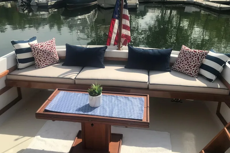 Oasis Yacht Photos Pics Cozy seating area on 1987 Wilbur 38 boat with decorative cushions and table.