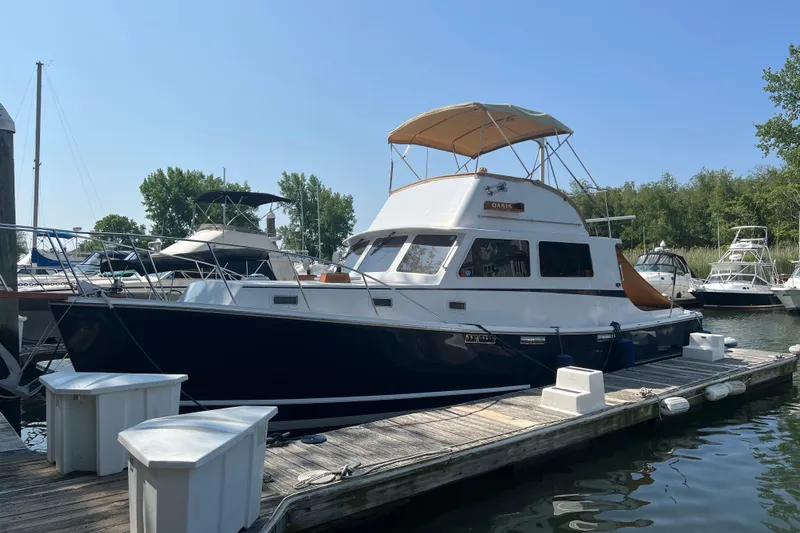 Oasis Yacht Photos Pics 1987 Wilbur 38 boat docked at marina, featuring a blue hull and tan canopy.
