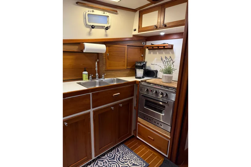 Oasis Yacht Photos Pics Compact 1987 Wilbur 38 boat kitchen with wooden cabinets, stainless steel sink, and oven.