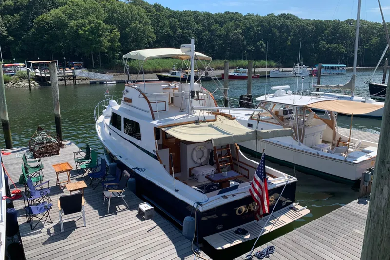 Oasis Yacht Photos Pics 1987 Wilbur 38 yacht docked at marina with outdoor seating and American flag.