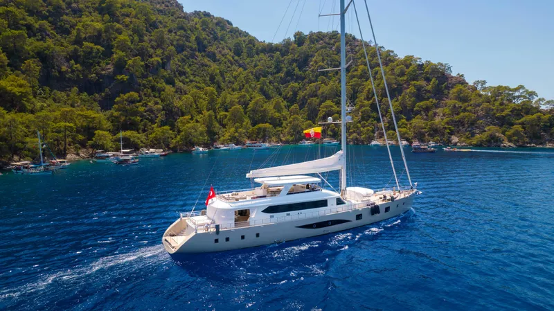 Ns02282 Yacht Photos Pics Custom Motorsailer 41M yacht sailing in clear blue waters near lush green coastline, 2023 model.