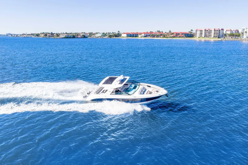  Yacht Photos Pics 2023 Sea Ray SLX 400 Outboard cruising on blue ocean near coastal buildings.