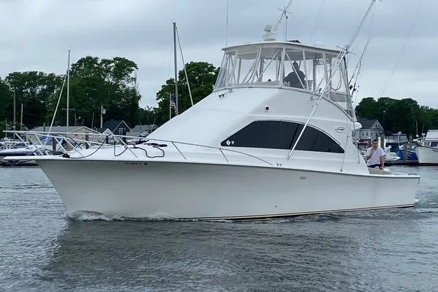 Reel It In Yacht Photos Pics 2003 Ocean Yachts 40 Super Sport cruising in a marina with lush greenery.