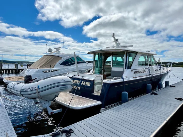 Calamity Jane Yacht Photos Pics 2018 Sabre 45 Salon Express yacht docked with inflatable boat, under cloudy sky.