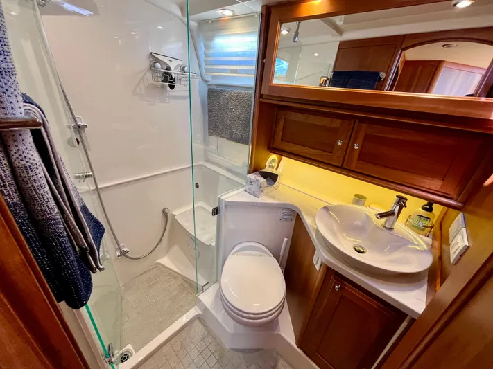 Calamity Jane Yacht Photos Pics Luxurious bathroom in 2018 Sabre 45 Salon Express yacht with shower, sink, and wooden cabinetry.