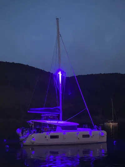  Yacht Photos Pics 2024 Lagoon 42 catamaran illuminated with blue lights at night on calm water.