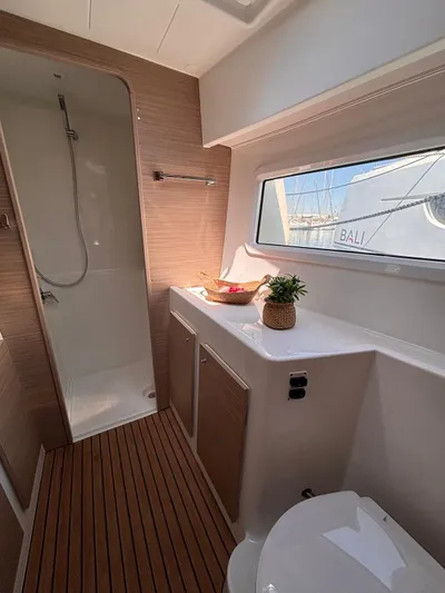  Yacht Photos Pics 2024 Lagoon 42 yacht bathroom with wooden flooring, shower, and window view.