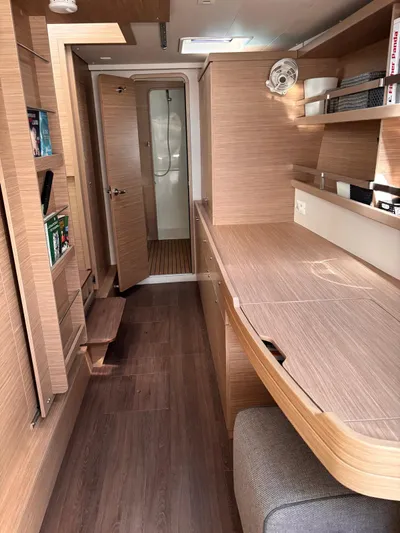  Yacht Photos Pics 2024 Lagoon 42 yacht interior with modern wood finish, shelves, and a compact bathroom.