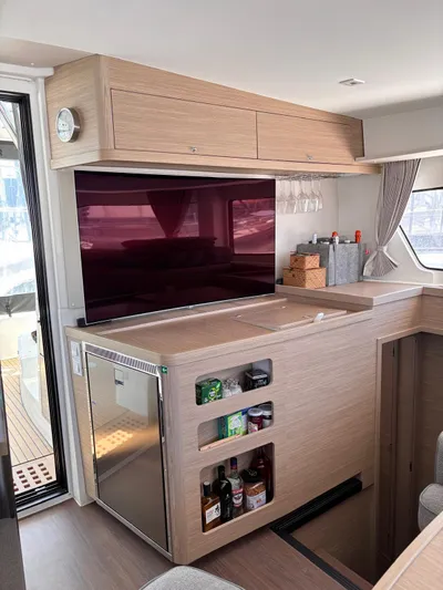  Yacht Photos Pics Modern interior of 2024 Lagoon 42 yacht with TV, storage, and mini fridge.